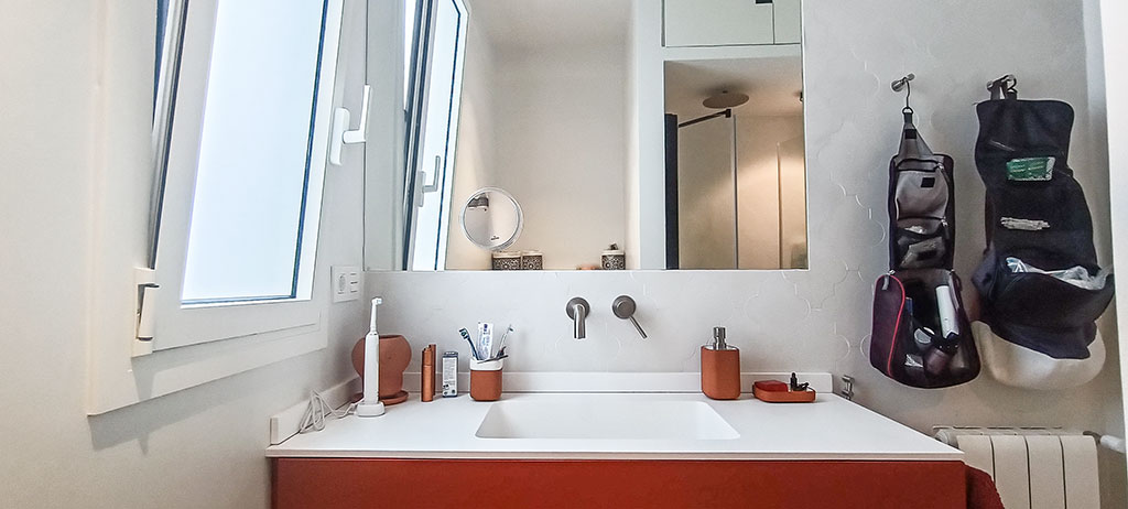 El Baño también se modifica, desplazando la ducha, haciéndola más corta y  ancha, más funcional. El lavabo colgado con encimera de compacto de resinas blanco y mueble laminado color teja, con una grifería de acero inoxidable empotrada en pared